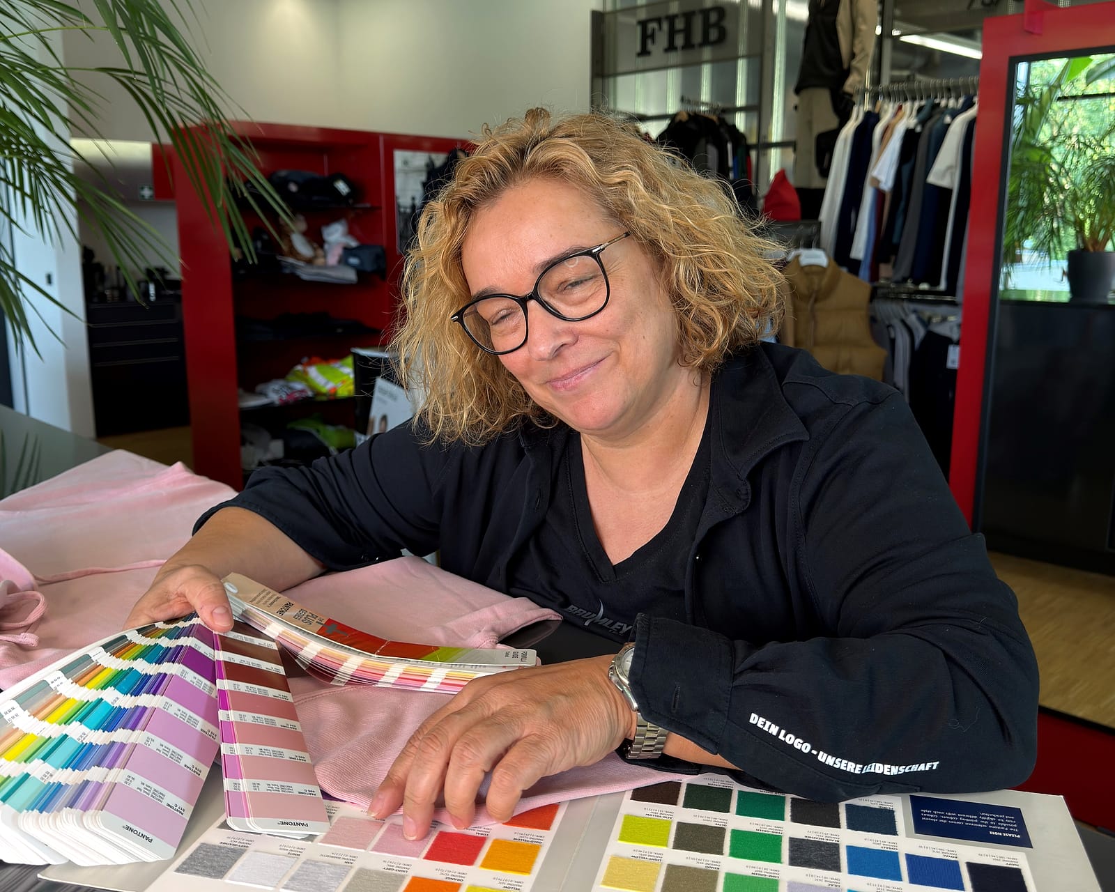 Britta Schneider wählt am Beratungstisch im JobOutfit-Showroom in Emsdetten Farben anhand von Farbfächern und Stoffkarten aus