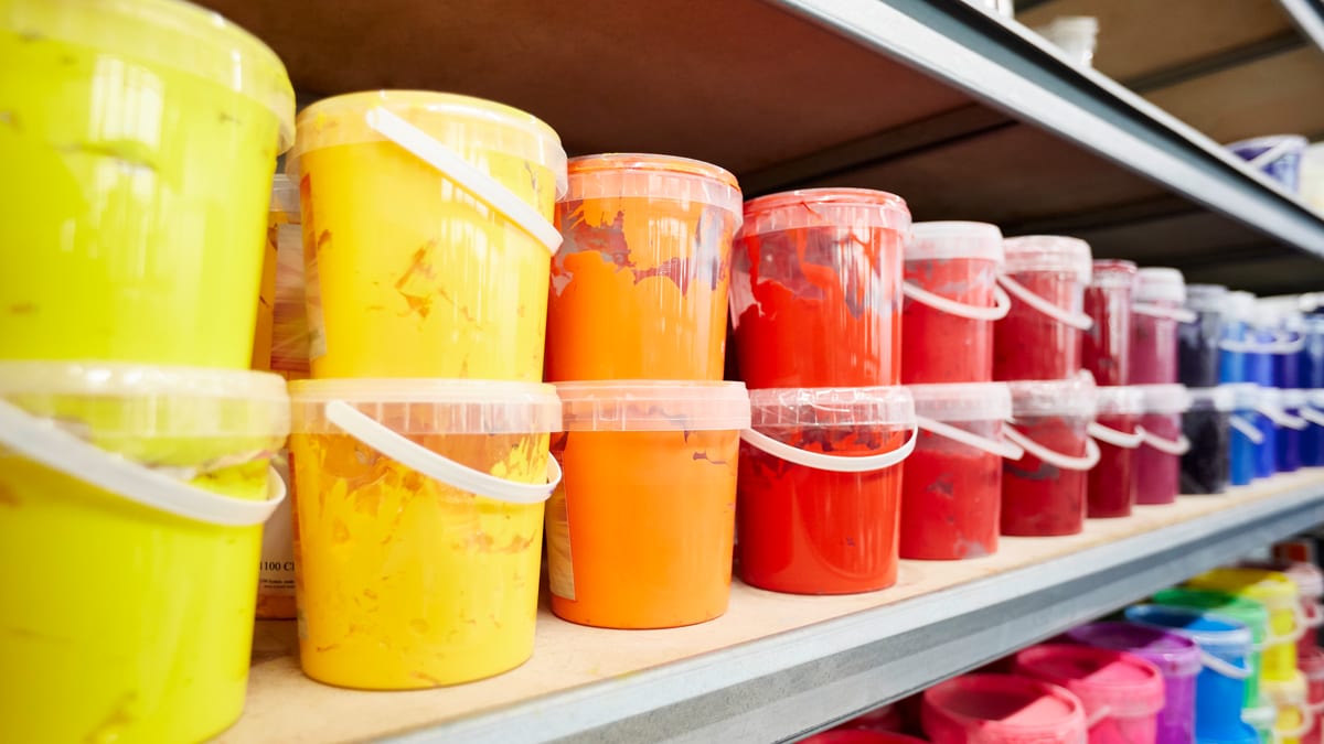 Regal mit Textildruckfarben in Gelb-, Orange-, Rot- und Blautönen